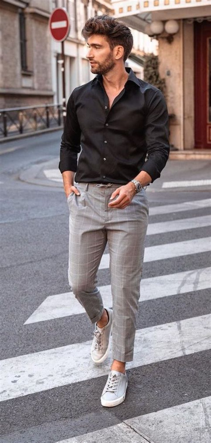 a man in black shirt and jeans standing on one leg with his hands out